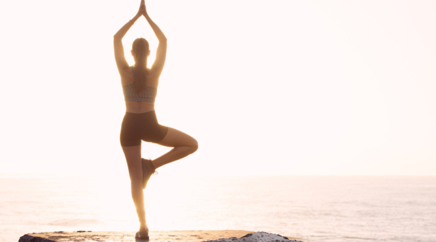 Young woman practicing yoga outdoors, embodying mindfulness and holistic wellness through yoga therapy. Discover the benefits of reconnecting with your body at Embodied Wellness Center.