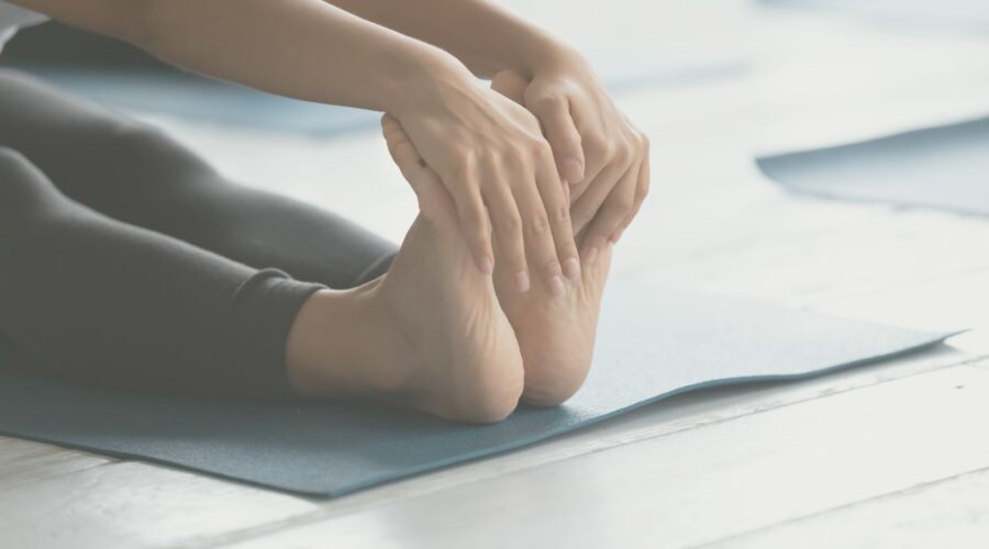 Woman practicing proprioception by stretching and reaching for her toes, demonstrating body awareness and holistic wellness at Embodied Wellness Center.