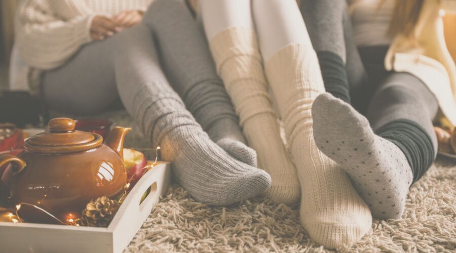 A group of women sitting together, wearing cozy wool socks, embodying the Danish hygge lifestyle by creating a warm and comforting atmosphere during winter.