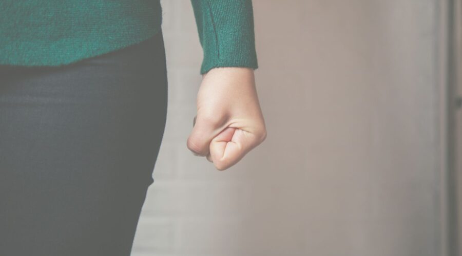 A woman clenching her fist, representing the physical manifestation of anger and the importance of healthy expression, as discussed in our "De-stigmatizing Anger" blog post.