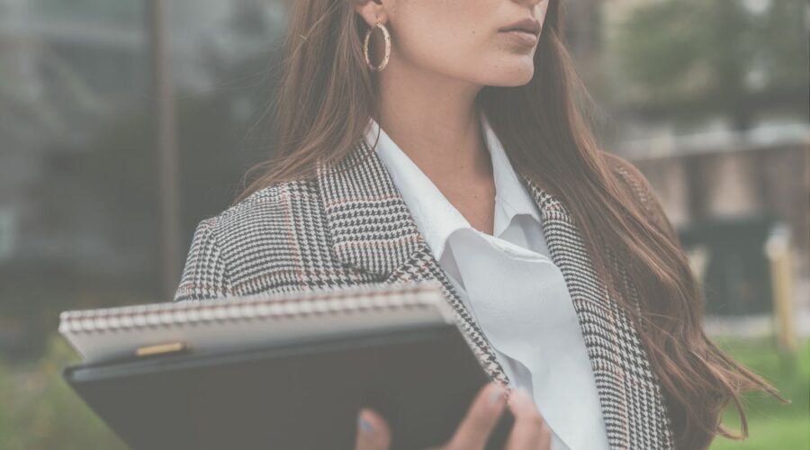 A confident woman holding notebooks, symbolizing organization and success, as she conquers impostor syndrome through mindfulness and positive affirmations.