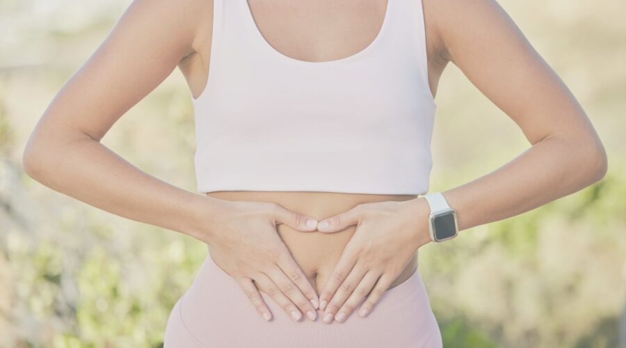 A woman placing her hands over her stomach, symbolizing the brain-gut connection and the importance of gut health for mental wellness. This image highlights the holistic approach to mental health through mindfulness and gut health, as discussed in our blog post on the brain-gut connection.