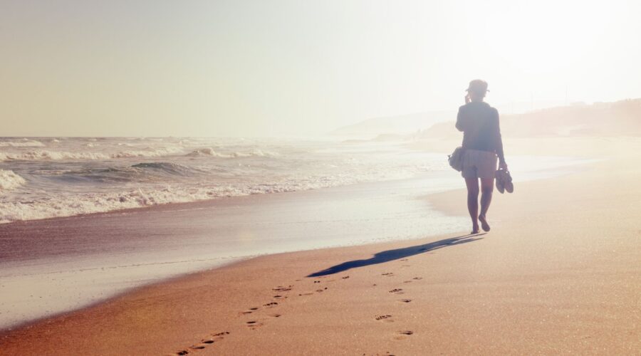 Woman practicing mindful walking on the beach, focusing on the sensory experience and presence, illustrating mindfulness techniques for daily activities in the blog "5 Activities to Try Mindfully Today."