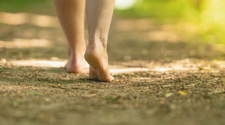 Woman walking barefoot on grass, practicing grounding techniques to reconnect with nature and find inner peace. Ideal for stress reduction and mindfulness, this practice helps restore balance and calm in everyday life.