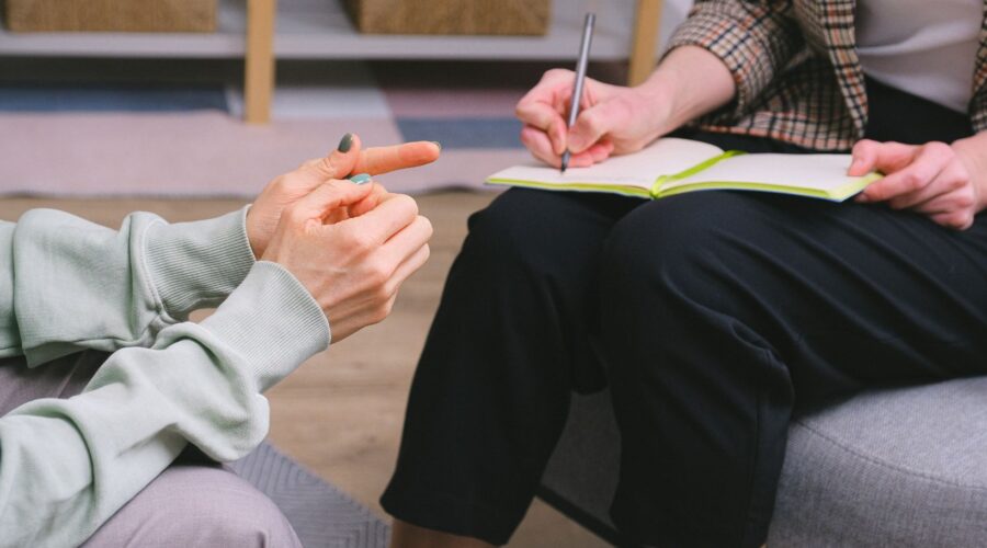 A therapist's hands taking notes during a neurodiversity-affirming therapy session, focusing on individualized care for a neurodivergent client. This image highlights the importance of tailored mental health support at Embodied Wellness Center, offering inclusive and holistic approaches for autism and ADHD.