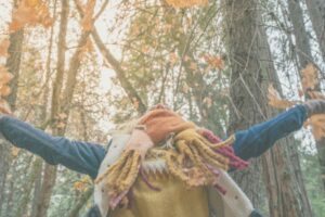 A woman joyfully tosses autumn leaves into the air, symbolizing the practice of letting go during the fall season. This serene image captures the essence of mindfulness and release, aligning with holistic wellness practices such as mindfulness, breathwork, and self-compassion. Ideal for illustrating tips on emotional healing and self-care during the transition of seasons in a "Five Holistic Ways to Practice Letting Go This Fall" blog post.