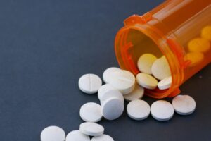 An orange prescription pill bottle with white tablets spilling out, symbolizing the risks of opioid misuse and addiction.